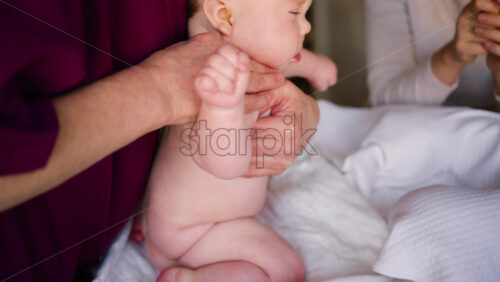 Baby lying on their back while an adult massages them and performs mobility exercises