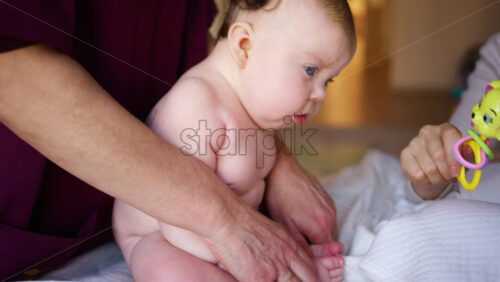 Caregiver doing mobility exercises with a baby, distracted by a toy