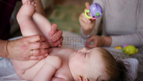 Baby lying on their back while an adult massages them and performs mobility exercises