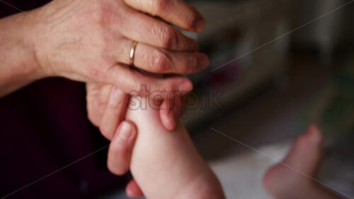 Close up of adult hands gently massaging a baby's foot and sole
