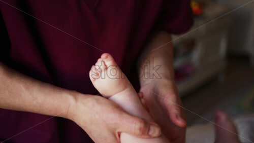 Close up of adult hands gently massaging a baby's foot and sole