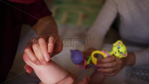 Close up of adult hands gently massaging a baby's foot and sole