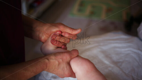 Close up of adult hands gently massaging a baby's foot and sole