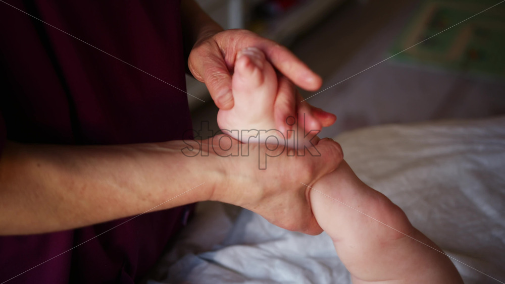 Close up of adult hands gently massaging a baby's foot and sole