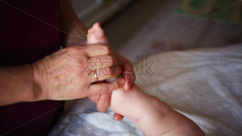 Close up of adult hands gently massaging a baby's foot and sole