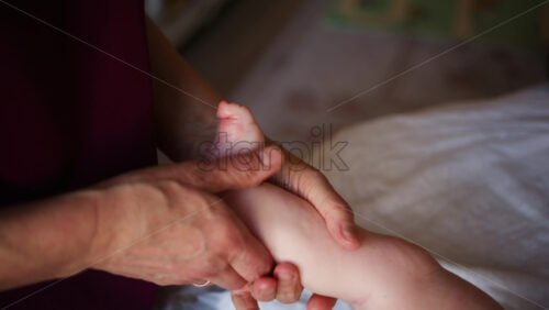 Close up of adult hands gently massaging a baby's foot and sole