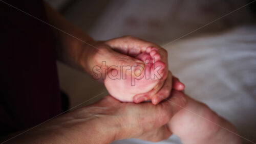 Close up of adult hands gently massaging a baby's foot and sole