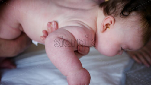 Caregiver doing mobility exercises with a baby, near the mother