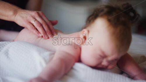 Baby lying on their tummy while an adult massages them and performs mobility exercises