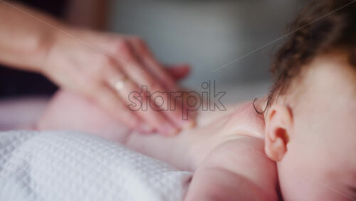 Baby lying on their tummy while an adult massages them and performs mobility exercises