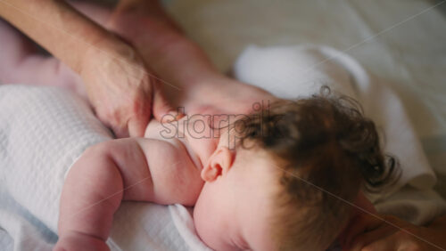 Baby lying on their tummy while an adult massages them and performs mobility exercises