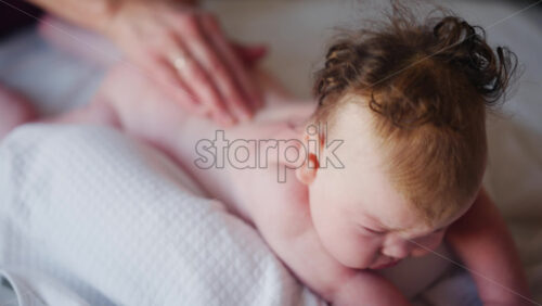 Baby lying on their tummy while an adult massages them and performs mobility exercises