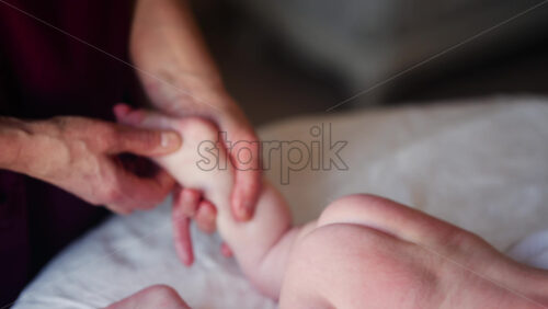 Baby lying on their tummy while an adult massages them and performs mobility exercises