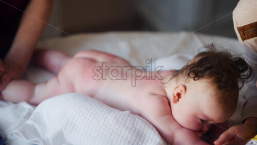 Baby lying on their tummy while an adult massages them and performs mobility exercises