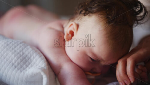 Baby lying on their tummy while an adult massages them and performs mobility exercises