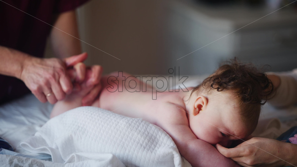 Baby lying on their tummy while an adult massages them and performs mobility exercises