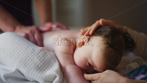 Baby lying on their tummy while an adult massages them and performs mobility exercises
