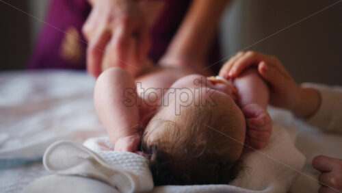 Baby lying on their back while an adult massages them and performs mobility exercises