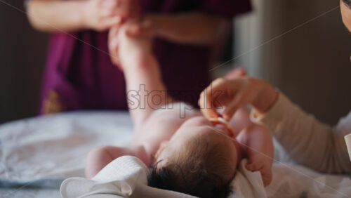 Baby lying on their back while an adult massages them and performs mobility exercises