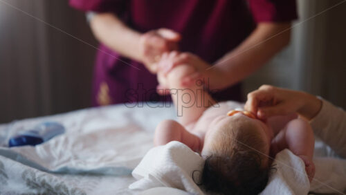 Baby lying on their back while an adult massages them and performs mobility exercises