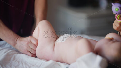 Baby lying on their back while an adult massages them and performs mobility exercises