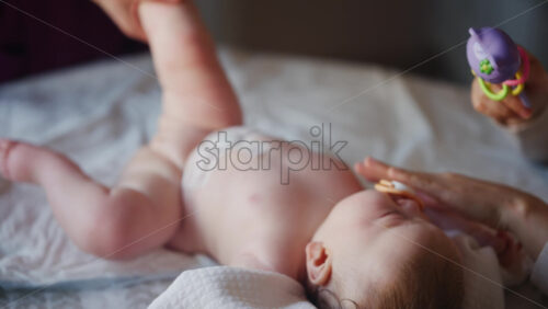 Caregiver doing mobility exercises with a baby, distracted by a toy