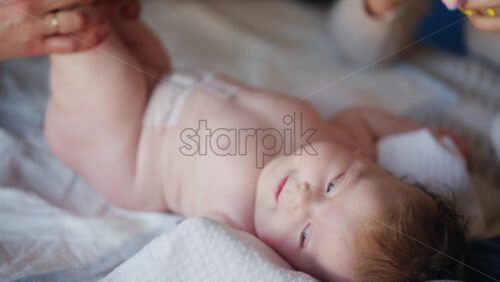 Caregiver doing mobility exercises with a baby, distracted by a toy