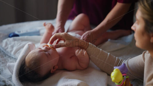 Woman trying to distract a crying baby lying on a blanket during massage with a toy