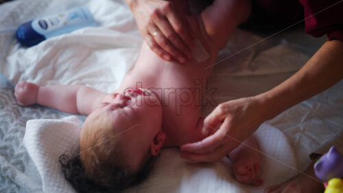 Baby lying on their back while an adult massages them and performs mobility exercises