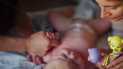 Caregiver doing mobility exercises with a baby, distracted by a toy