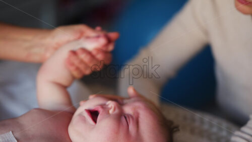 Close up of adult hands gently massaging a baby's arm and palm