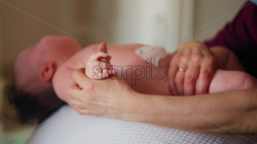 Baby placed on a stability ball while adults support the infant's body