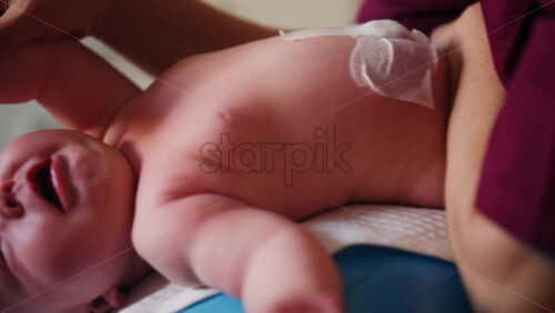 Baby placed on a stability ball while adults support the infant's body