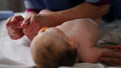 Baby lying on their back while an adult massages them and performs mobility exercises