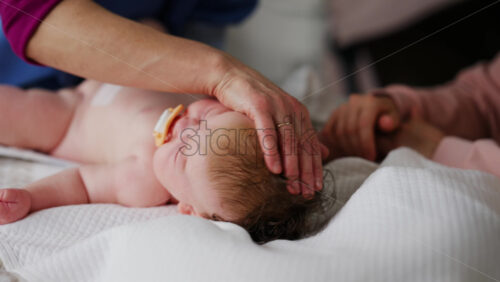Baby lying on their back while an adult massages them and performs mobility exercises