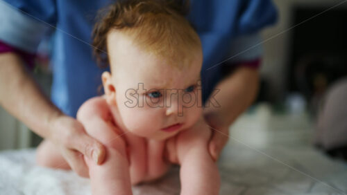 Baby lying on their back while an adult massages them and performs mobility exercises