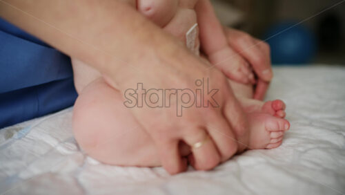 Baby lying on their back while an adult massages them and performs mobility exercises