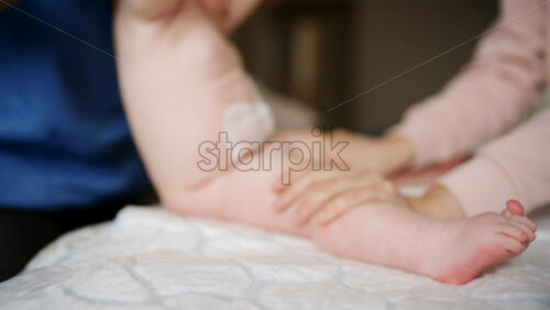 Close up of adult hands gently massaging a baby's foot and sole
