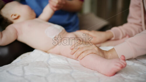 Baby lying on their back while an adult massages them and performs mobility exercises