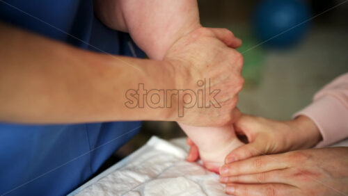 Close up of adult hands gently massaging a baby's foot and sole