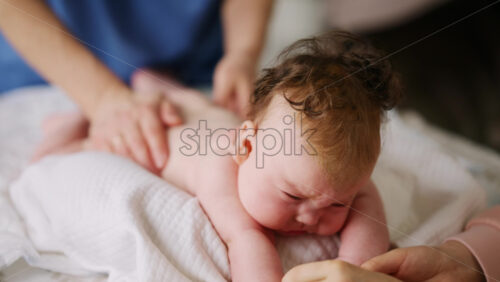Baby lying on their tummy while an adult massages them and performs mobility exercises