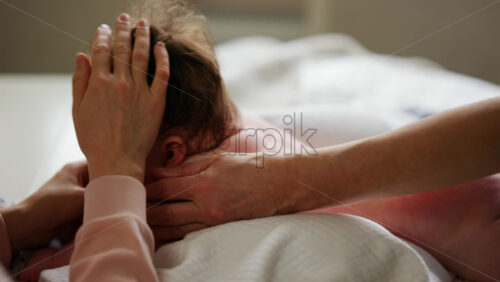 Baby lying on their tummy while an adult massages them and performs mobility exercises