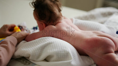 Baby lying on their tummy while an adult massages them and performs mobility exercises