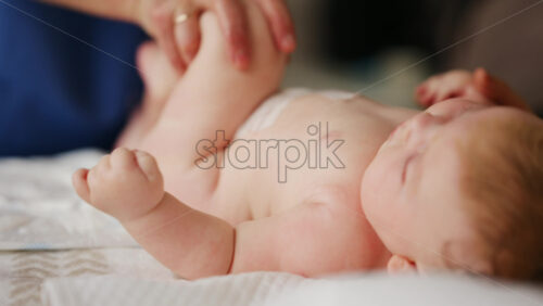 Baby lying on their back while an adult massages them and performs mobility exercises