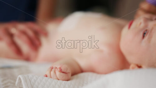 Baby lying on their back while an adult massages them and performs mobility exercises