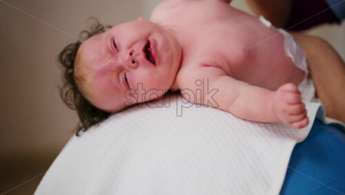 Baby placed on the back on a stability ball while adults support the infant's torso and shoulders
