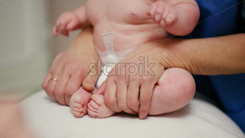 Baby placed on a stability ball while adults support the infant's body