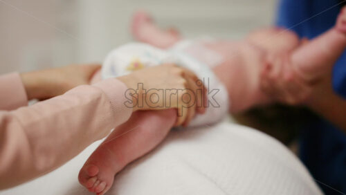 Baby placed on a stability ball while adults support the infant's body
