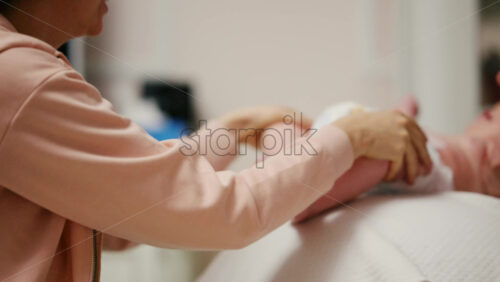 Baby placed on a stability ball while adults support the infant's body