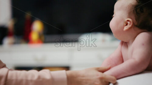 Baby lying on their tummy while an adult massages them and performs mobility exercises